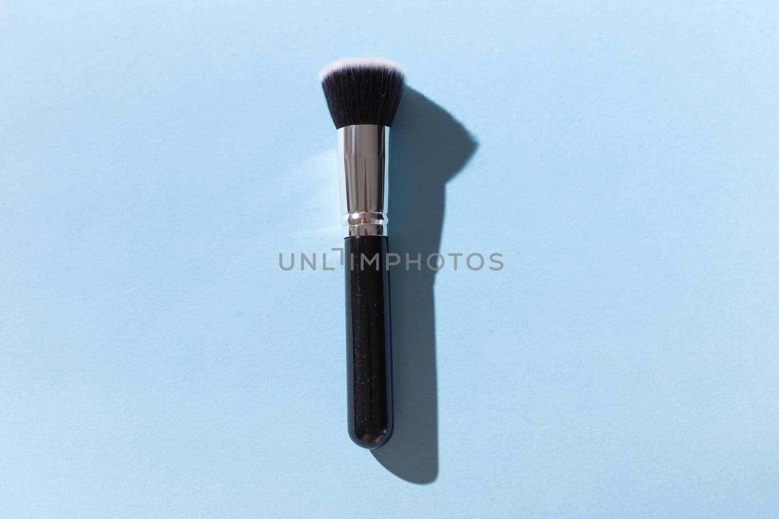 Make up brush on blue background, top view. by Satura86