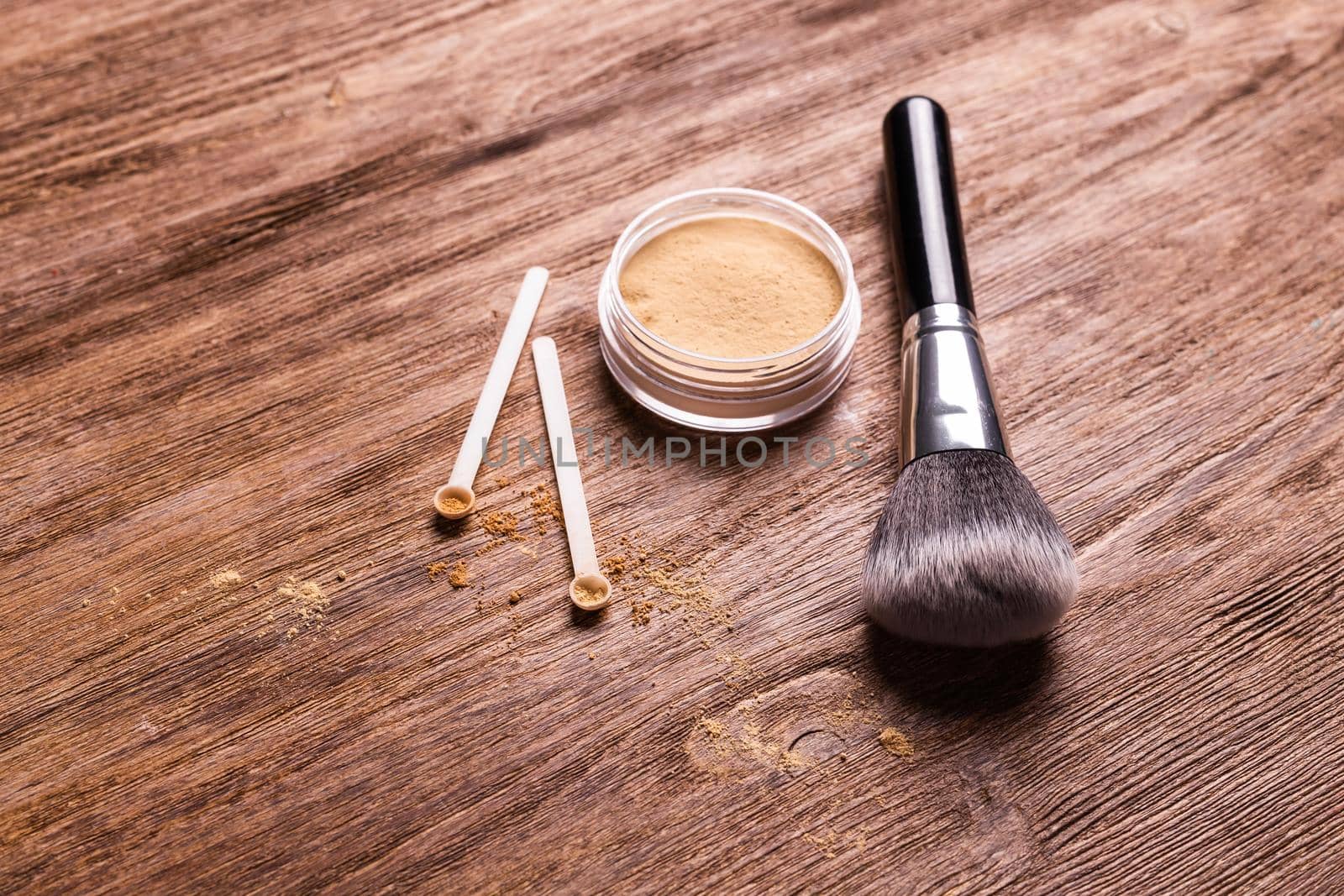 Mineral powder of different colors with spoon dispenser for make-up on wooden background.