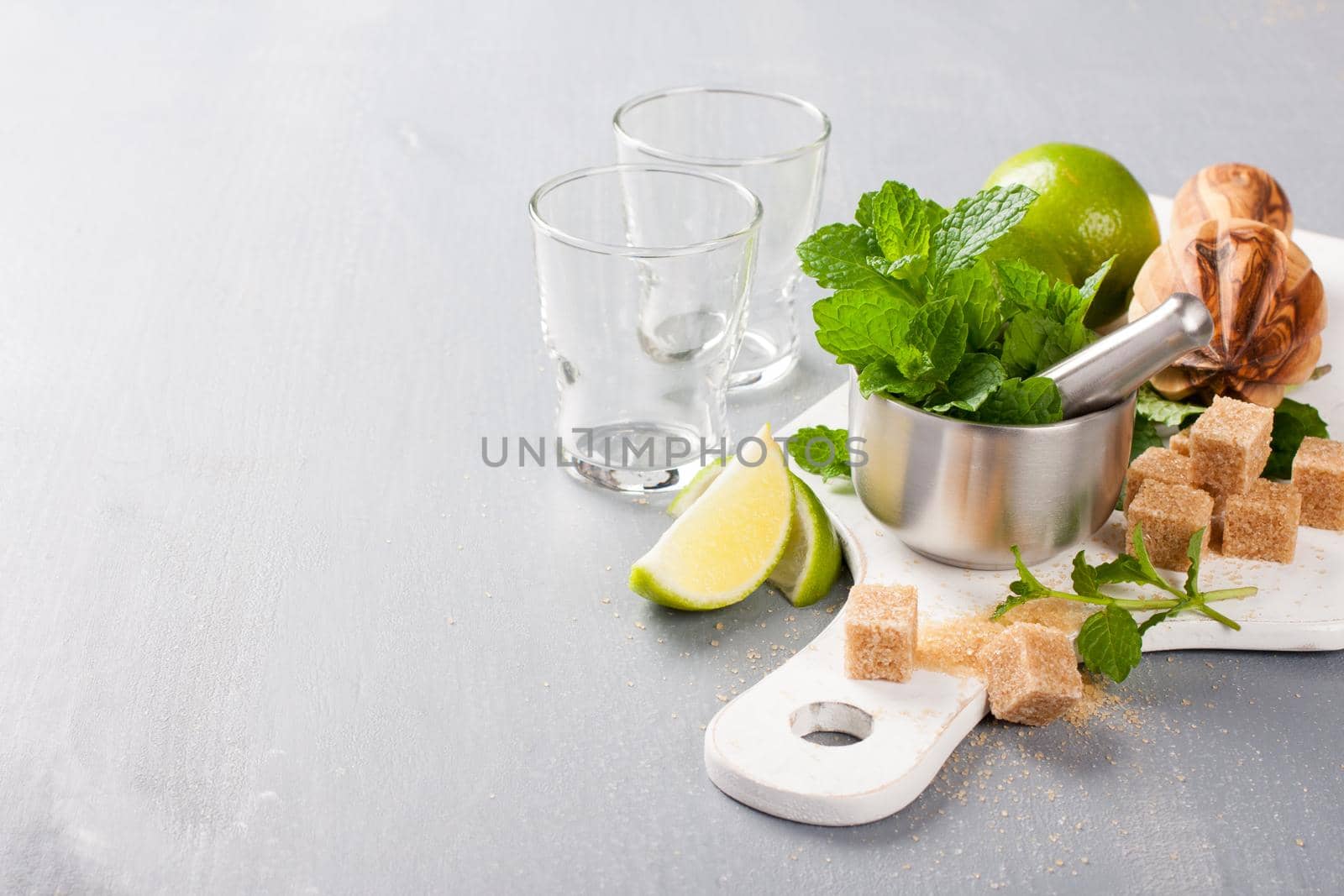 Metal mortar and pestle with fresh mint and ingredients for mojito, caipirinha cocktails and other drinks. Selective focus. Background with empty copy space.