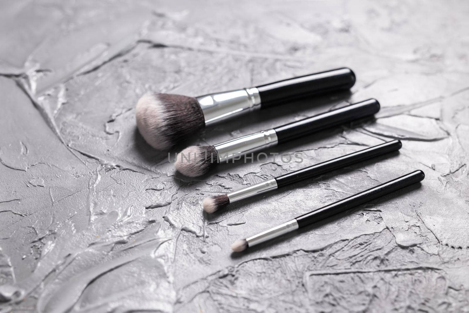 Top view of make-up brushes on grey background.