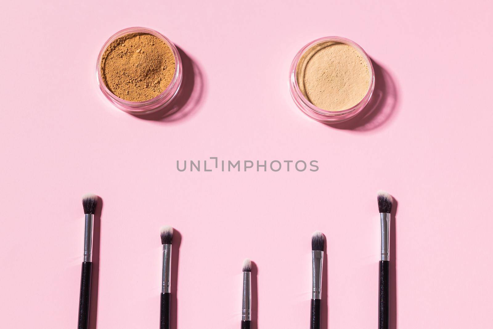 Various make-up brushes on pink background, top view. Cosmetics and beauty