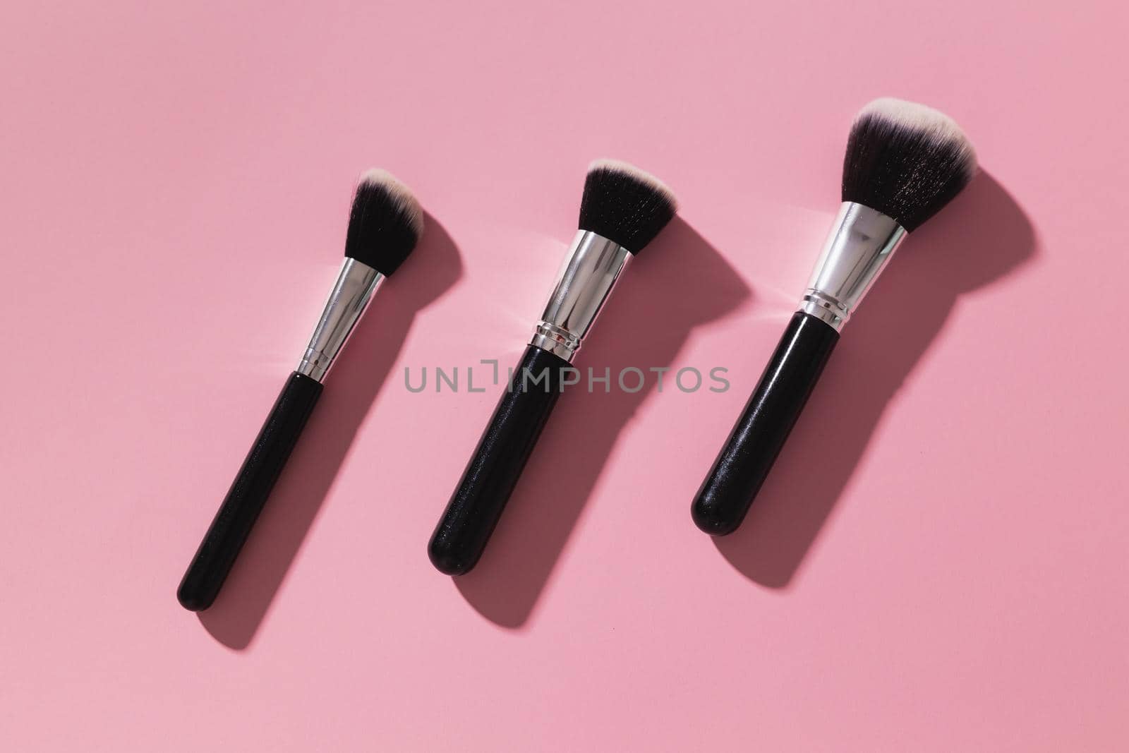 Various make-up brushes on pink background, top view. Cosmetics and beauty