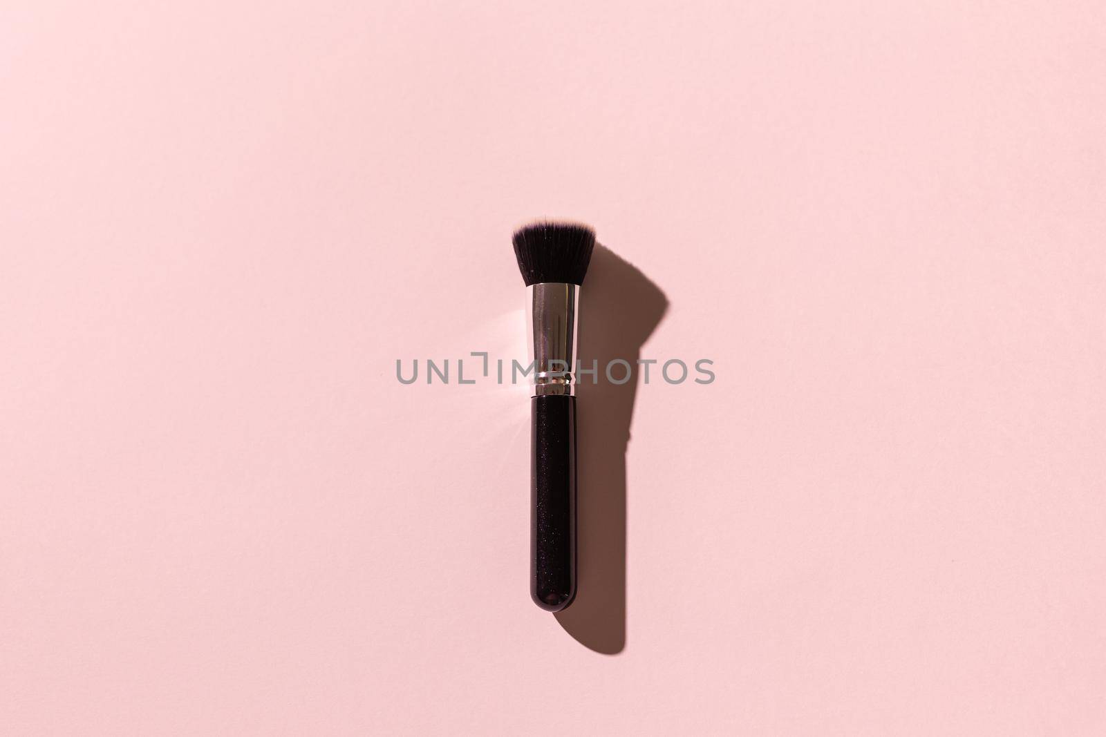 Make-up brush on pink background, top view. Cosmetics, beauty and skin care concept