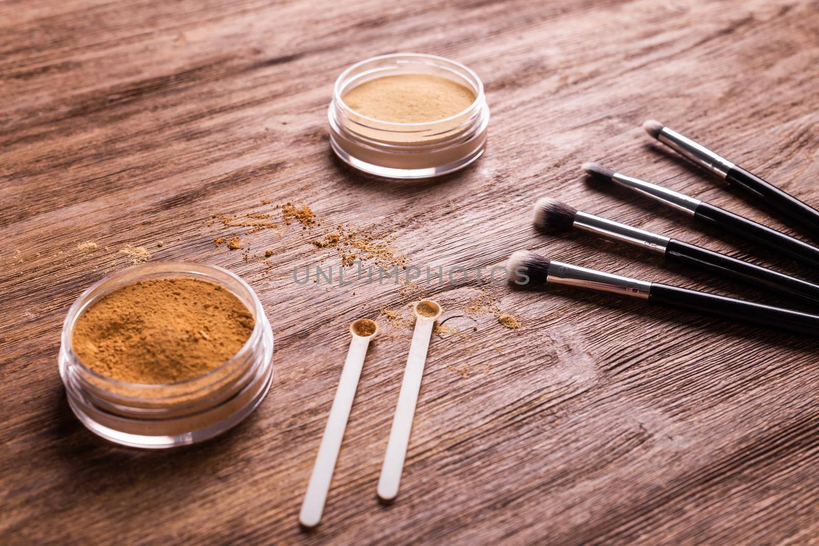 Mineral powder foundation with brushes on a wooden background. Eco-friendly and organic beauty products by Satura86