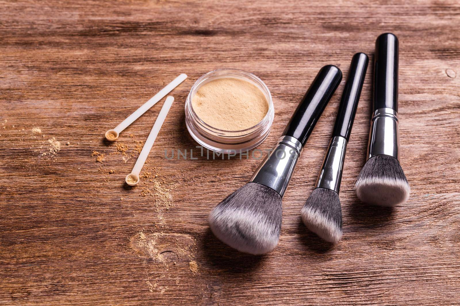 Mineral powder of nude colors with a spoon dispenser for make-up on wooden background by Satura86