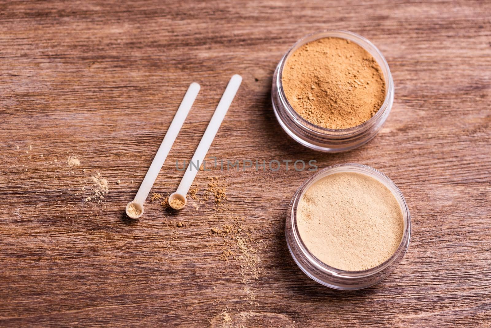 Mineral powder of different colors with spoon dispenser for make-up on wooden background.