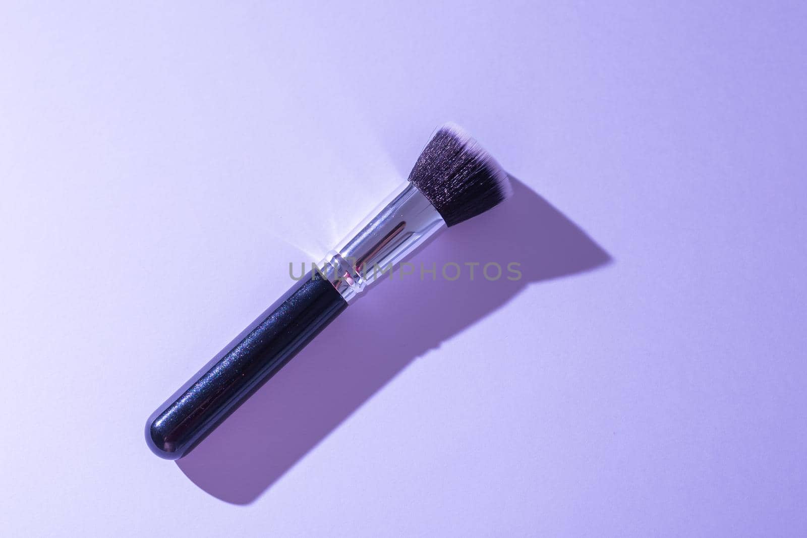 Make up brush on turquoise background, top view