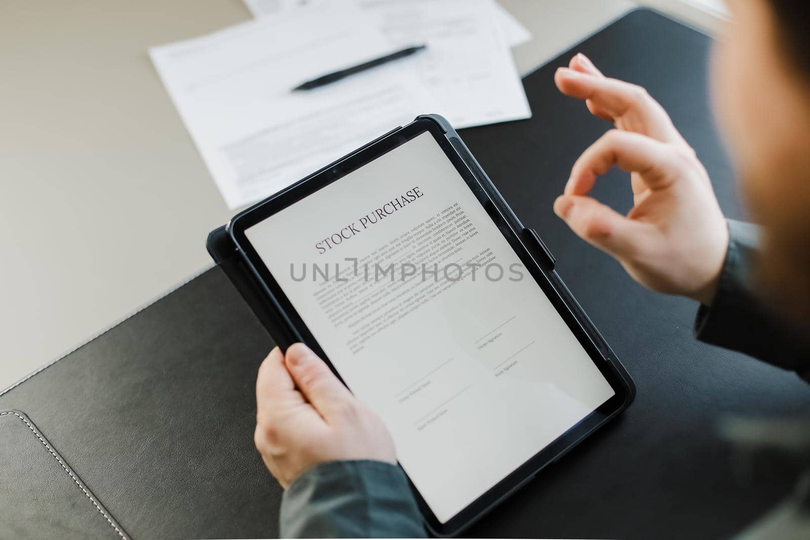 Man reading stock purchase agreement on tablet and showing ok gesture at office. Concept of filling documents.