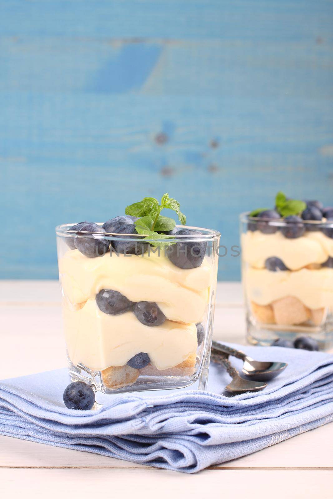 Fresh blueberry layered desert with mascarpone cream and cookies in glass