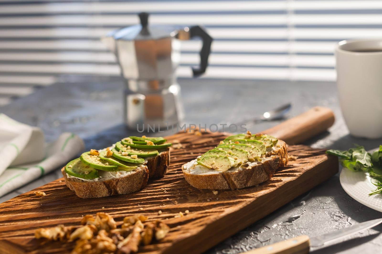 Sliced avocado on toast bread with nuts and coffee. Breakfast and healthy food concept. by Satura86