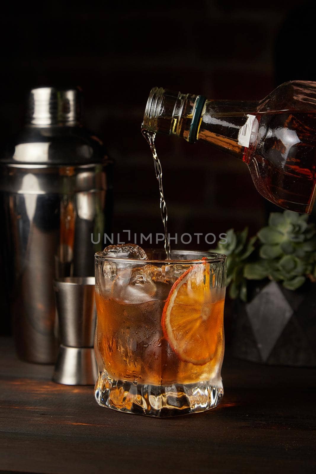 Old Fashioned in which whiskey is poured on a wooden background