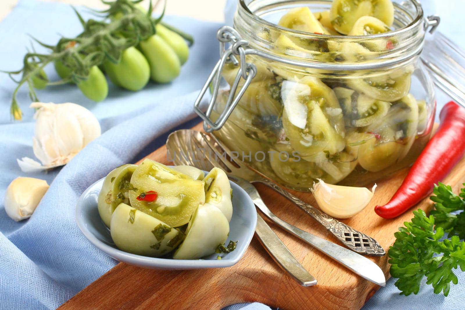 Pickled green tomatoes in blue bowl and in glass jar
