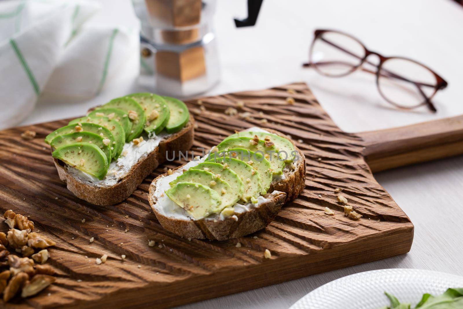 Sliced avocado on toast bread with nuts. Breakfast and healthy food concept. by Satura86