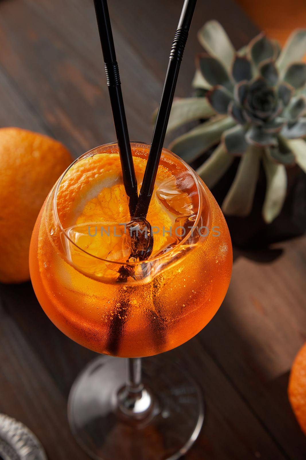 Aperol Spritz on top on a wooden background with an orange in the background. High quality photo