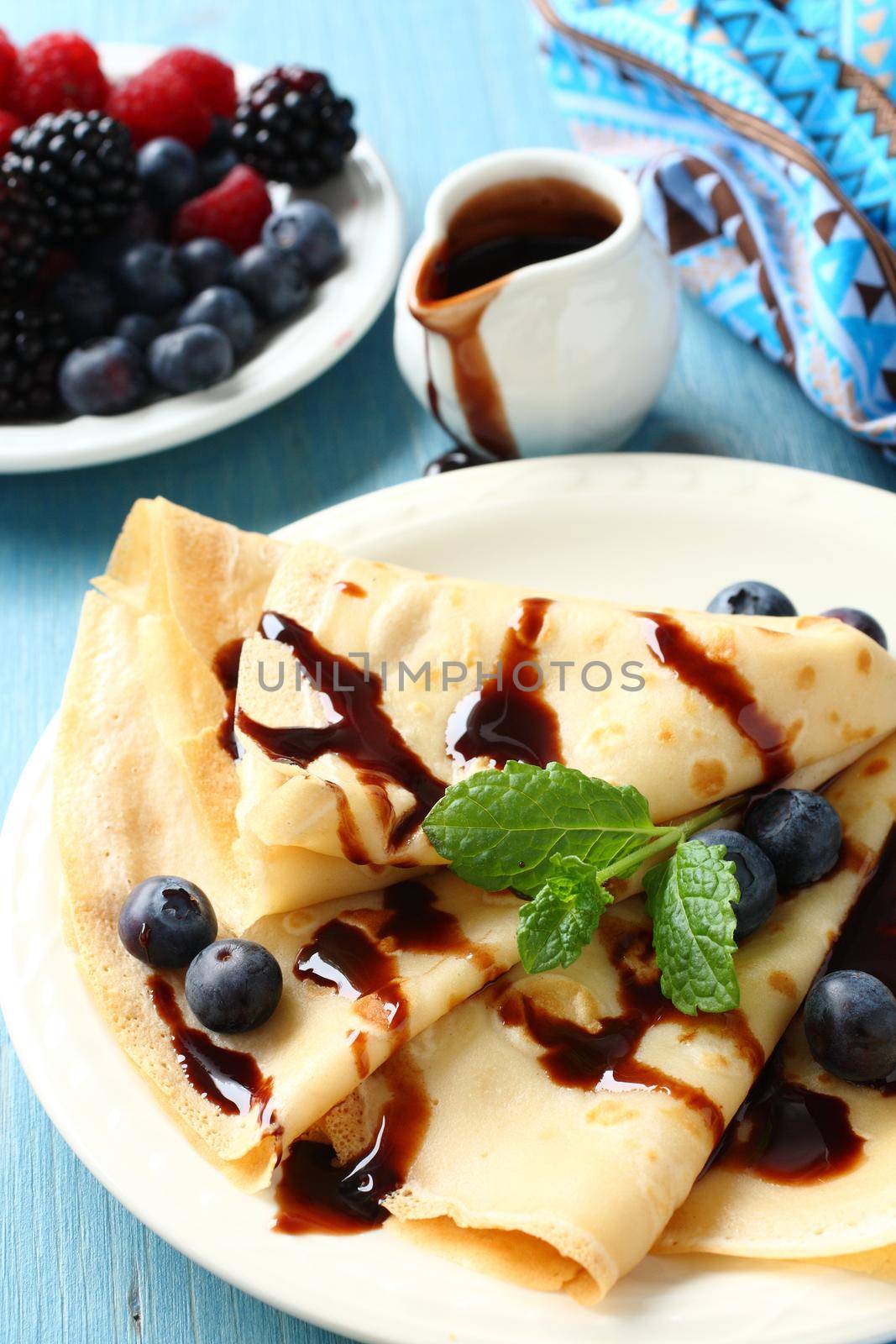 Homemade crepes with blueberries, chocolate sauce and mint