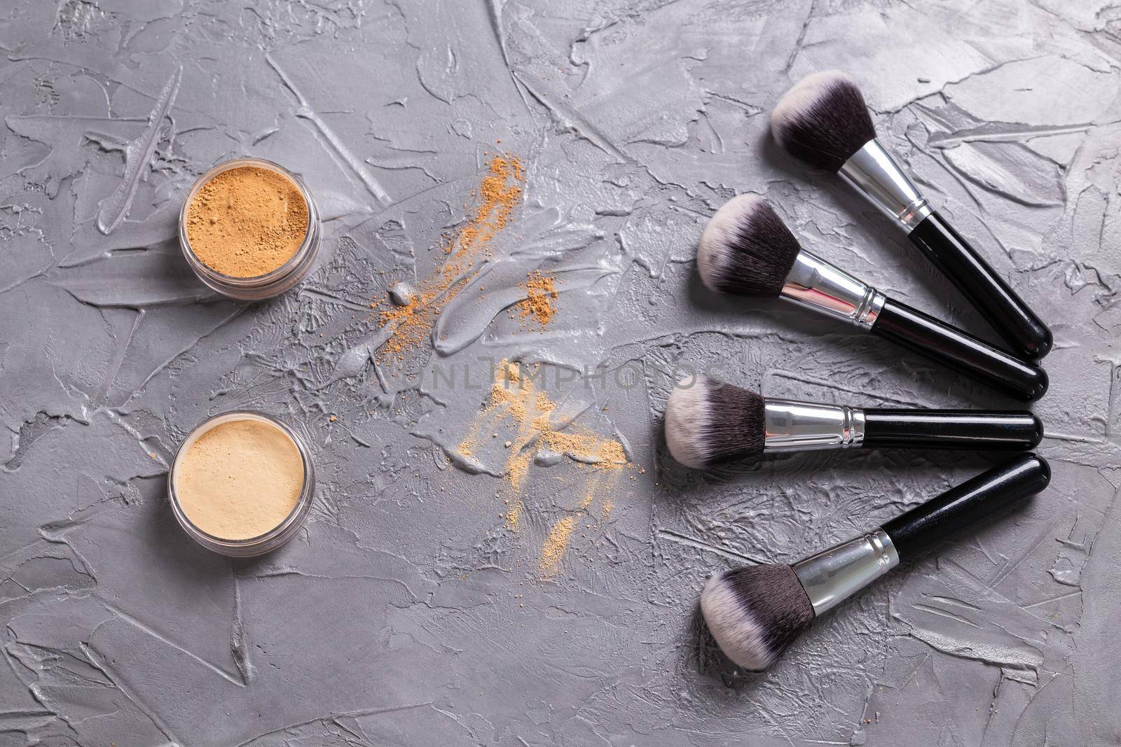 Mineral powder of different colors with a brushes for make-up on wooden background