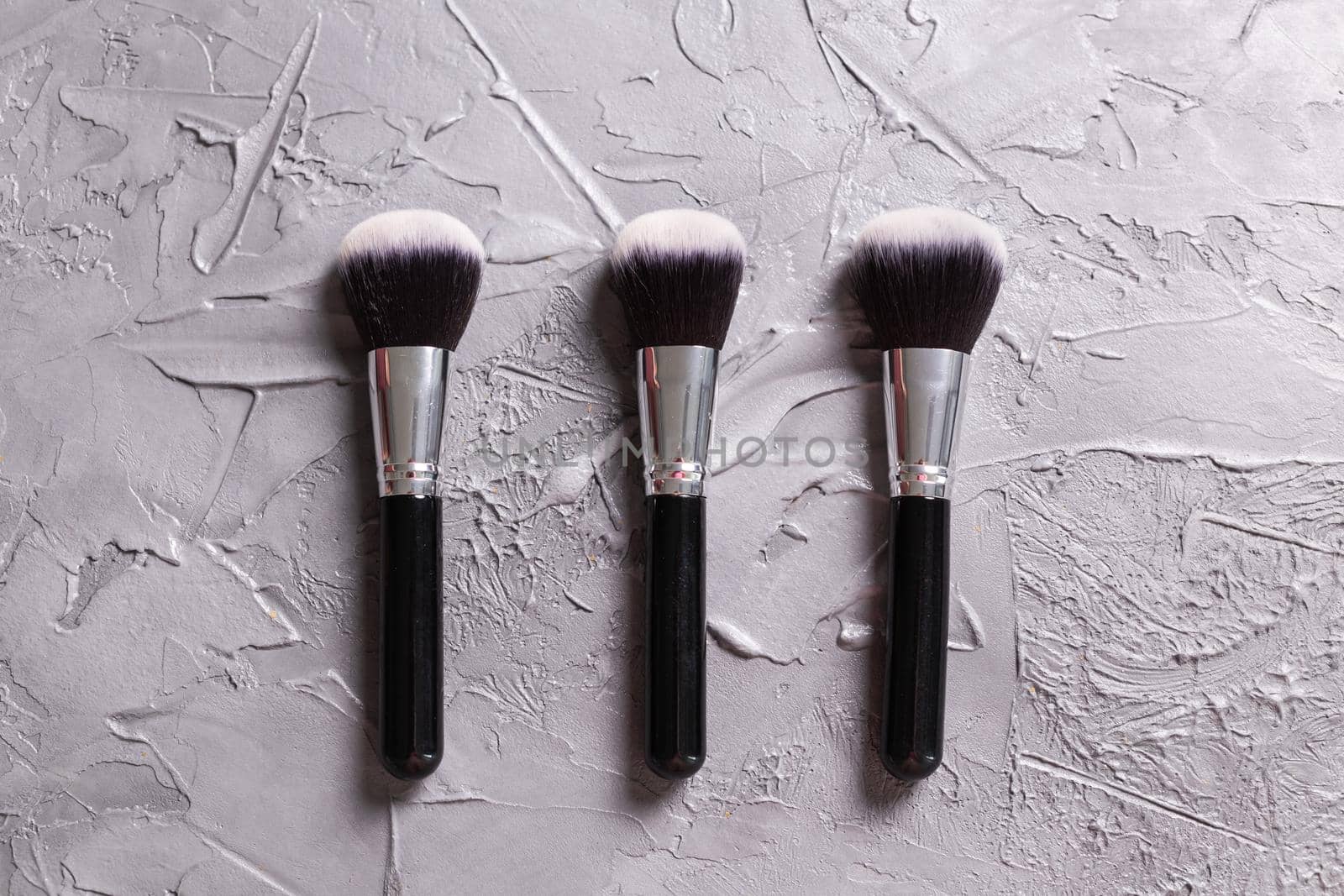 Top view of make-up brushes on grey background by Satura86