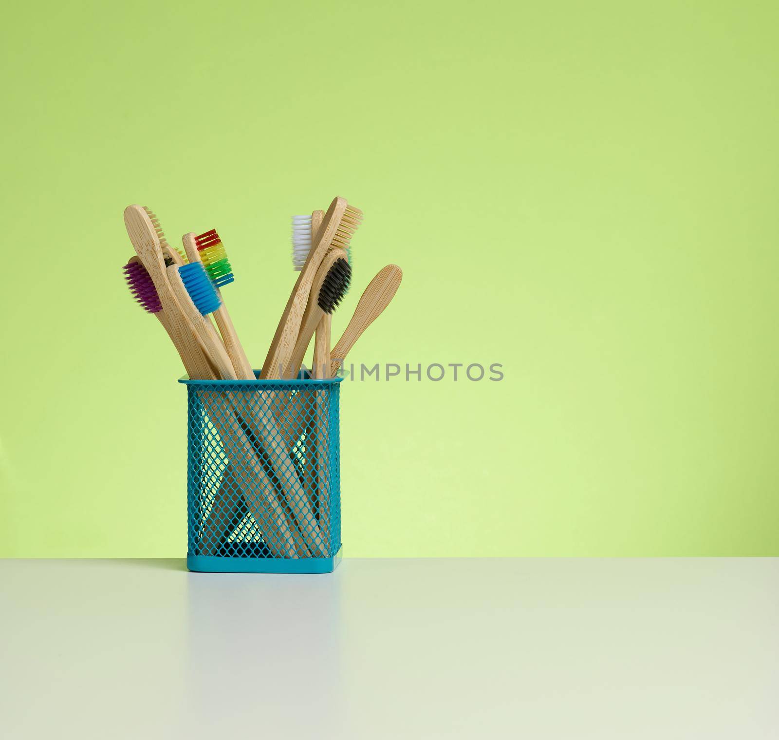 wooden toothbrushes in a plastic cup on a white table by ndanko
