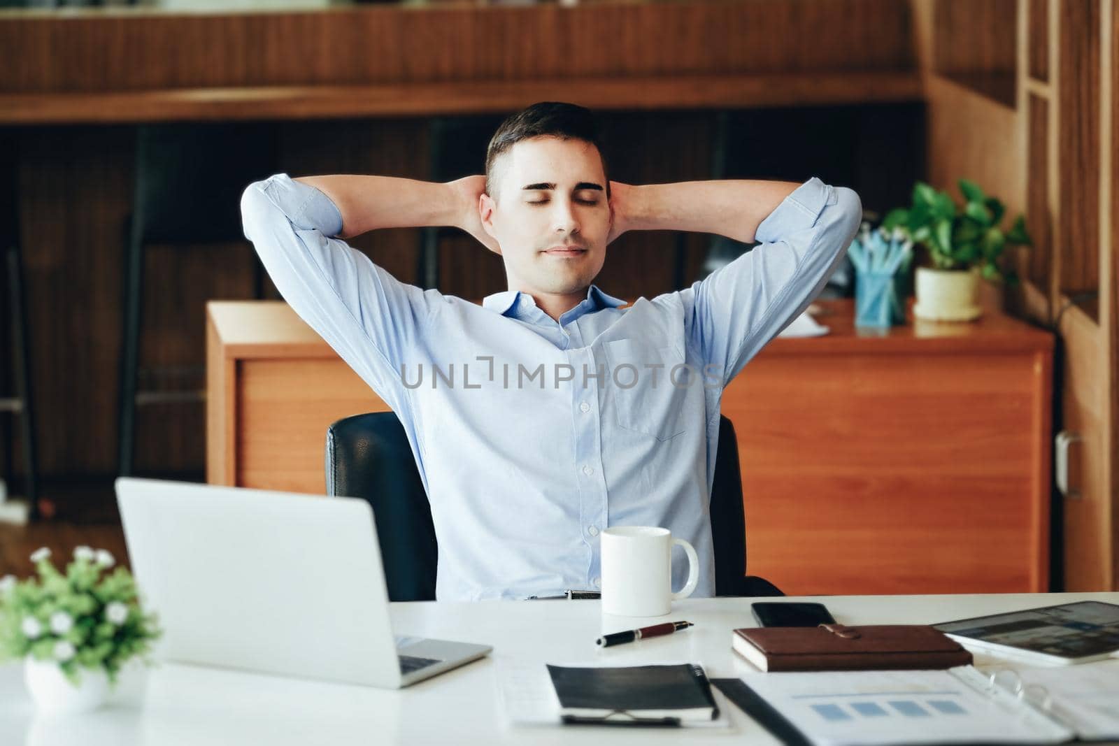 Male marketing manager resting and smiling while working to reduce drowsiness before using computers, iPads and marketing materials