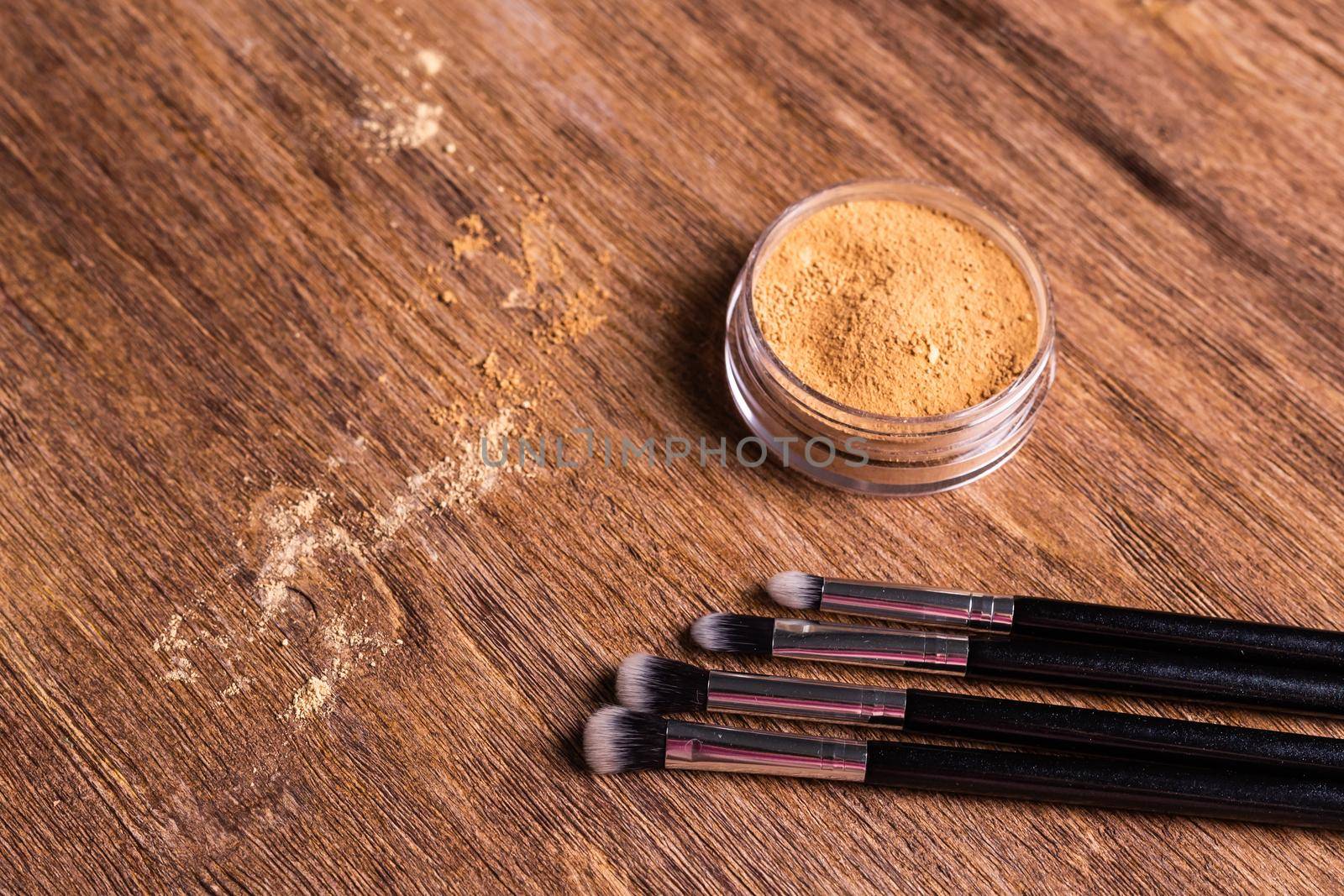 Mineral powder foundation with brush on a wooden background.