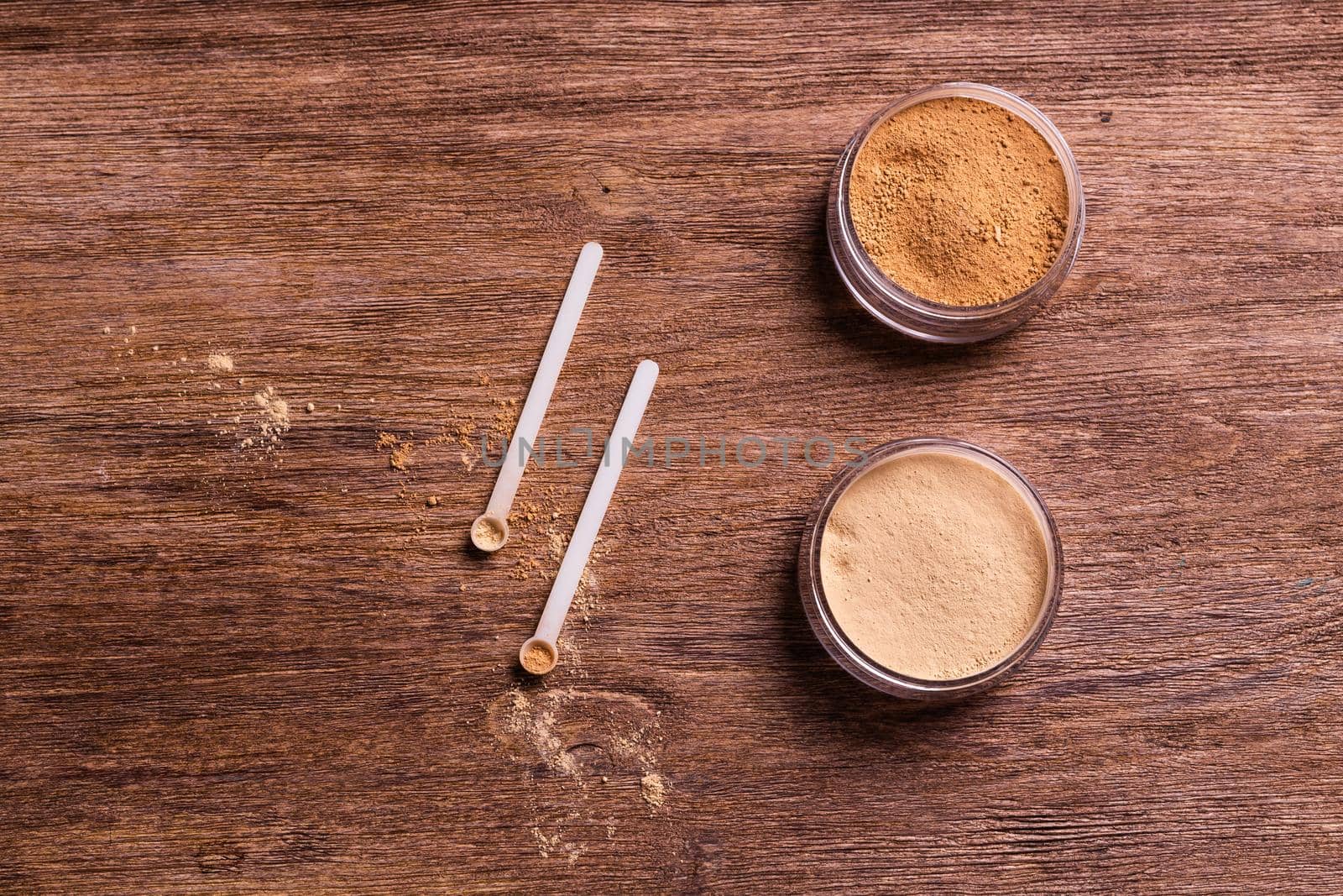 Mineral powder of different colors with spoon dispenser for make-up on wooden background.
