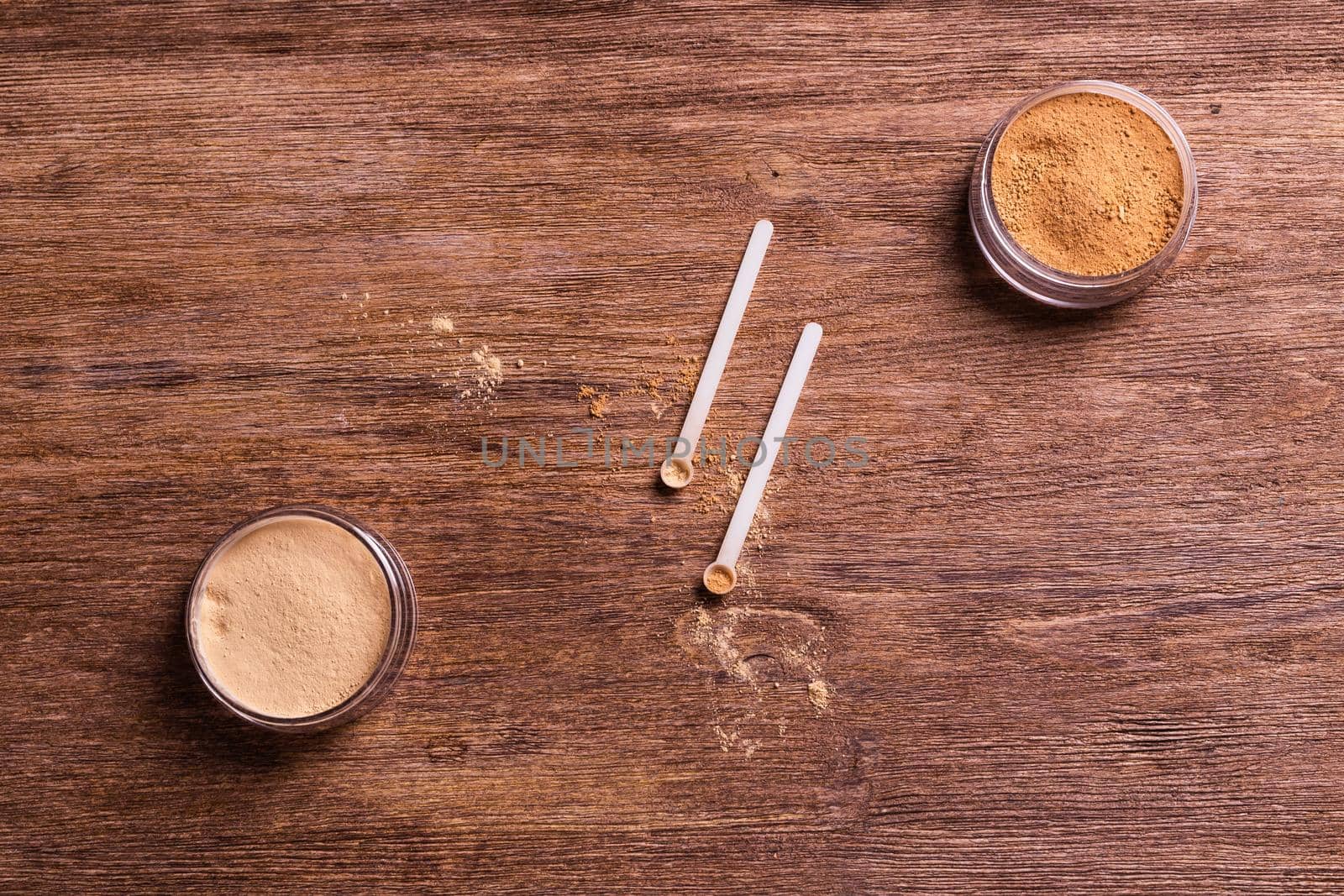 Mineral powder of different colors with spoon dispenser for make-up on wooden background.