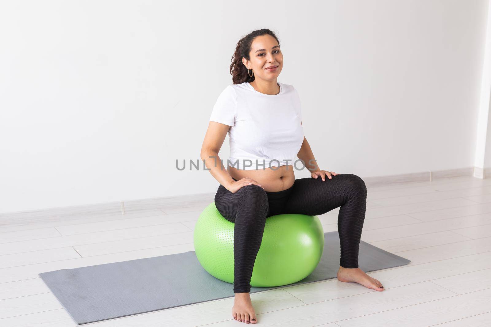 beautiful young pregnant woman doing exercise at home on fitball.