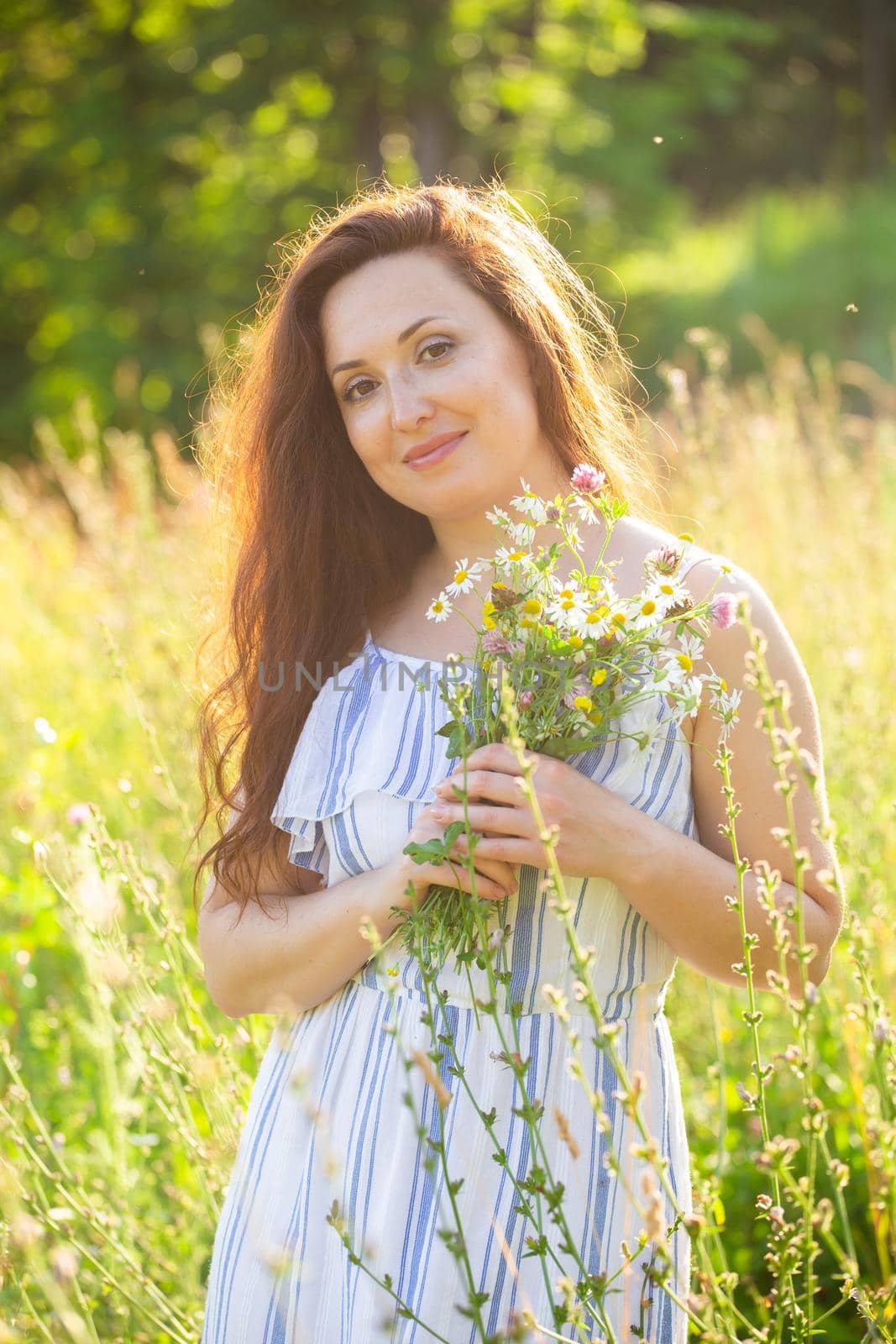 Young woman walking among wildflowers on sunny summer day. Concept of the joy of communicating with summer nature by Satura86