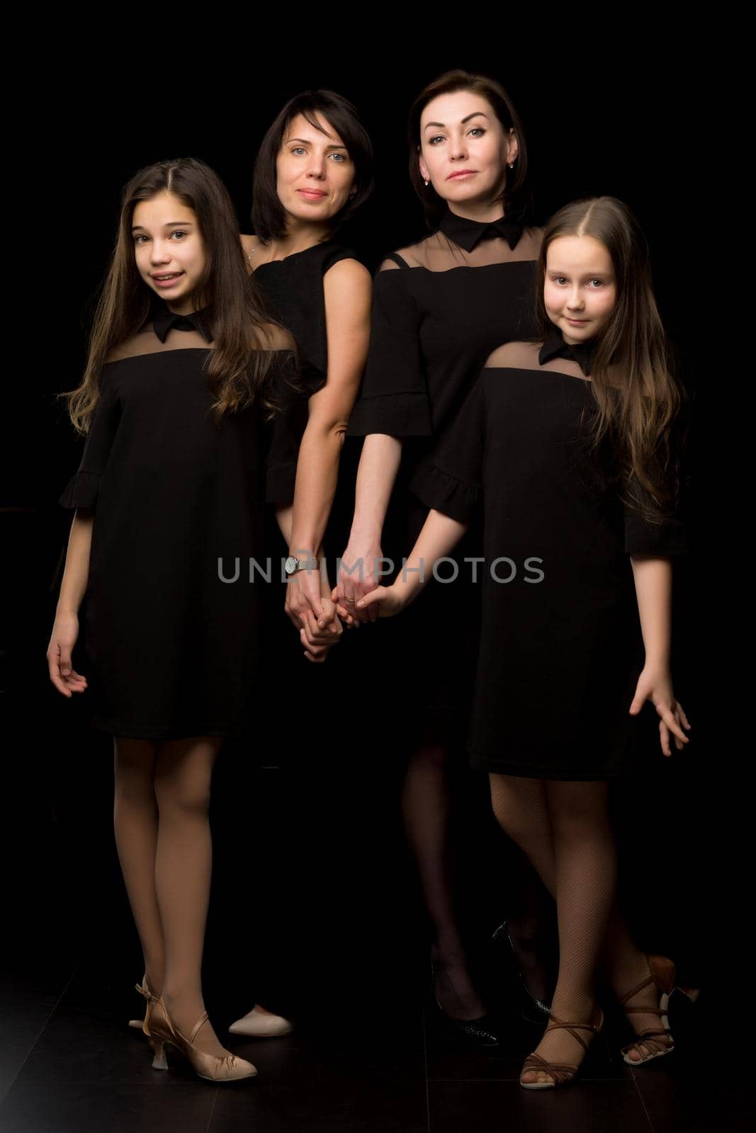 Group portrait on a black background. Young, Beautiful mothers with two charming daughters.