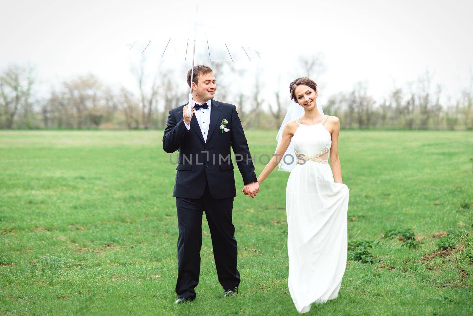 bride and groom on a rainy wedding day walking under an umbrella