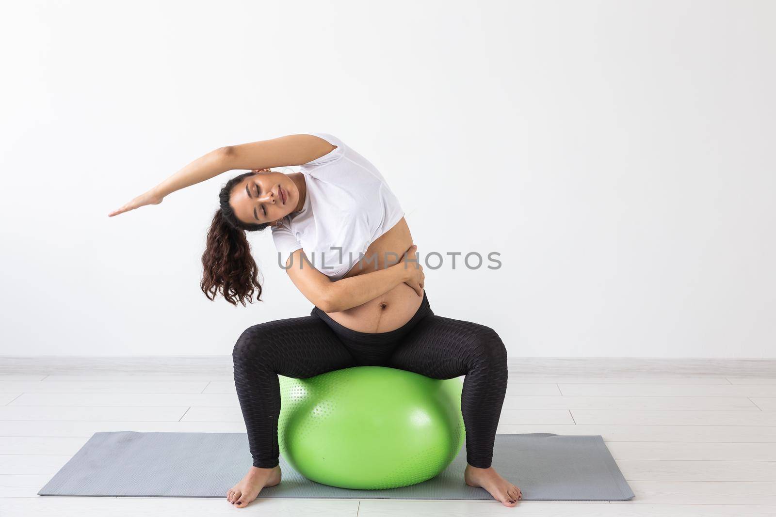 beautiful young pregnant woman doing exercise at home on fitball.