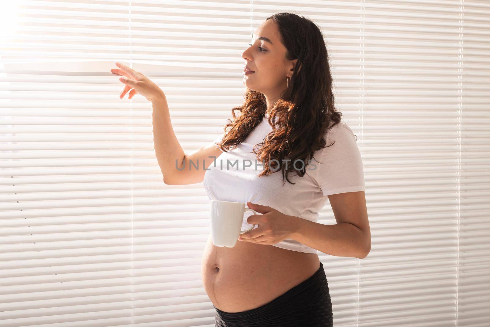 Pregnant woman eating croissant and drinks coffee. Pregnancy and maternity leave.