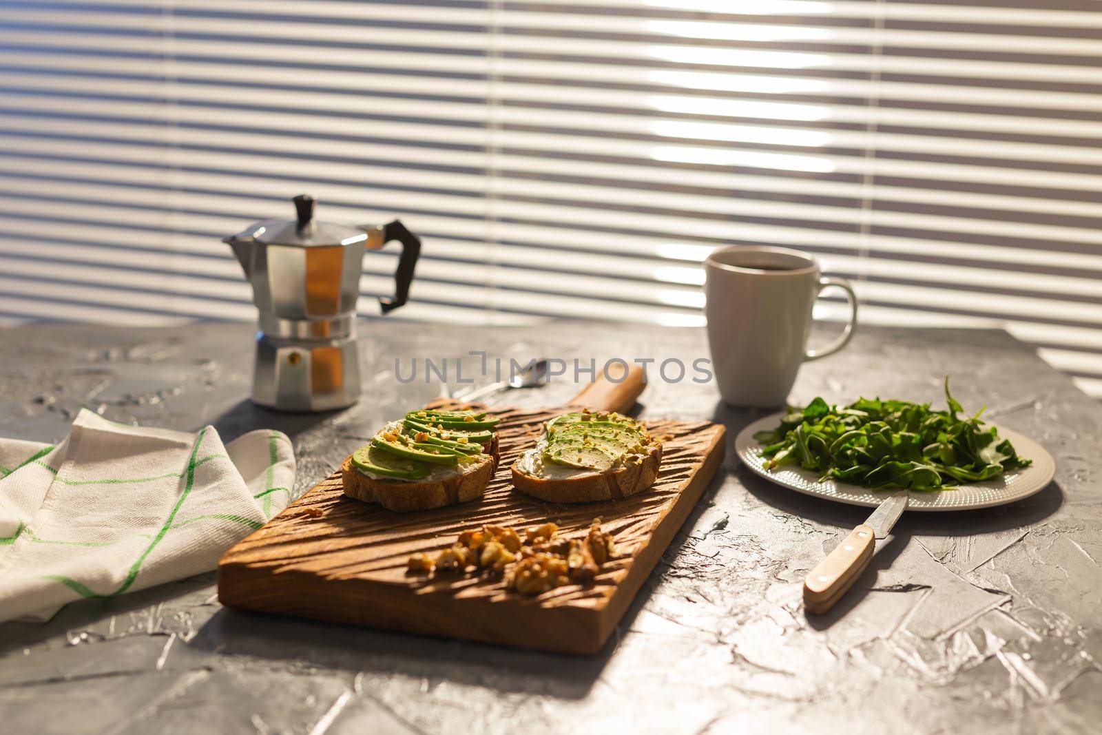 Sliced avocado on toast bread with nuts and coffee. Spinach on a plate and moka pot. Breakfast and healthy food