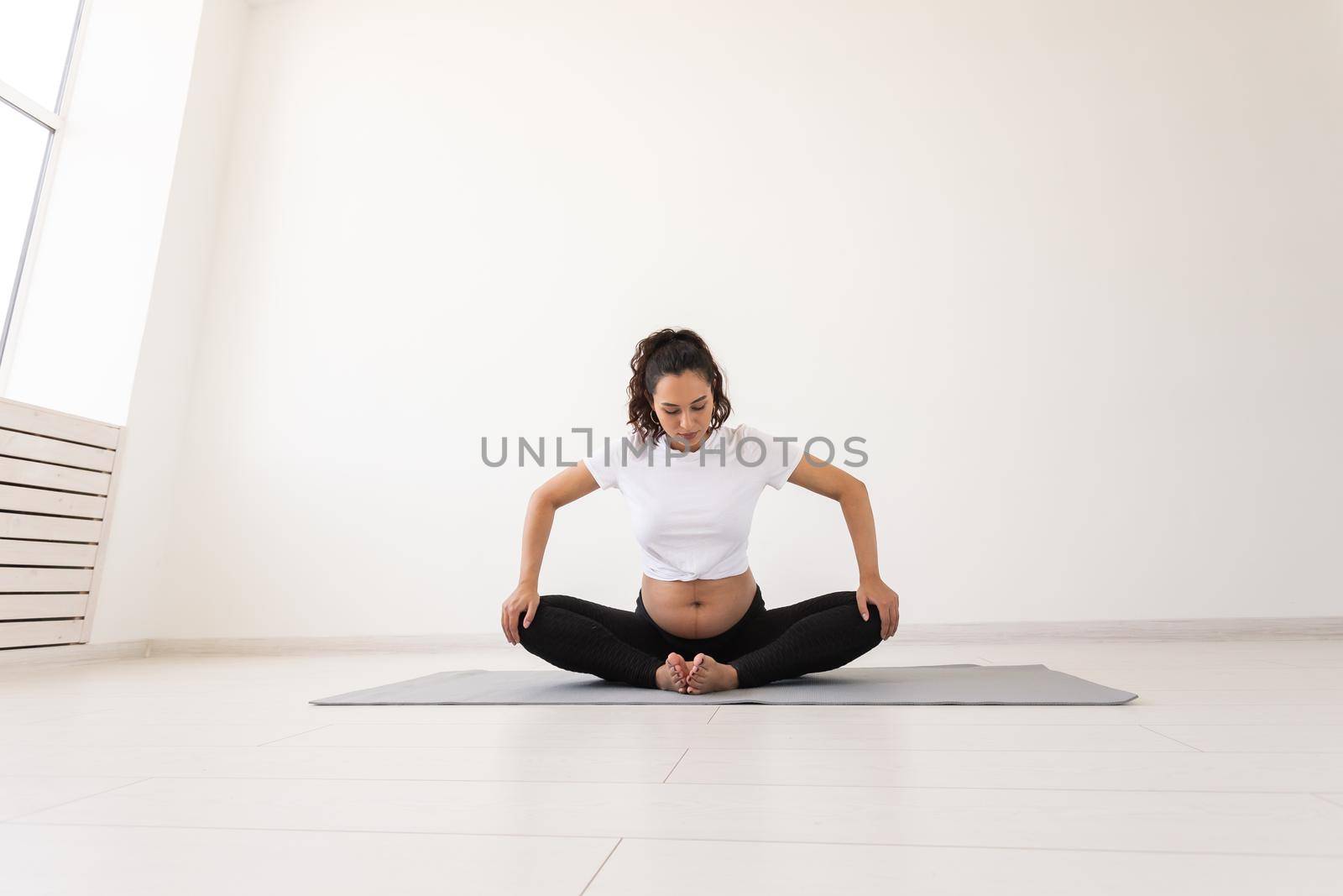 Purposeful pregnant woman exercises during yoga class and relaxes while sitting on a mat on the floor. Physical and mental preparation of the body for childbirth. Place for text