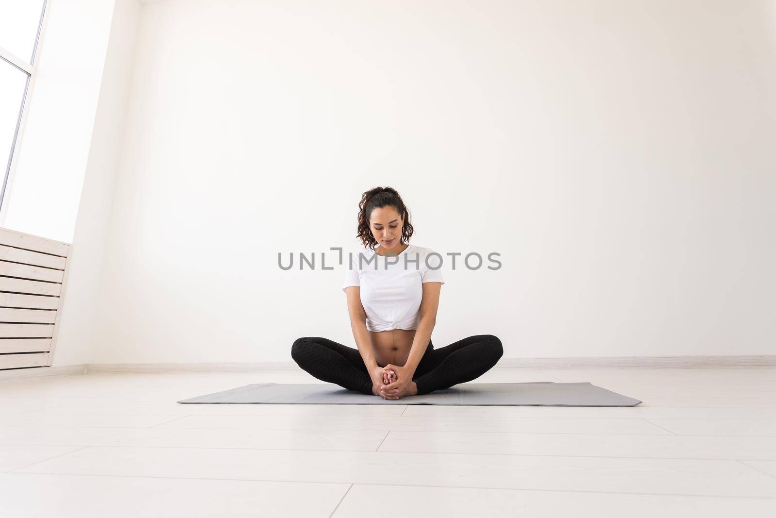 Purposeful pregnant woman exercises during yoga class and relaxes while sitting on a mat on the floor. Physical and mental preparation of the body for childbirth. Place for text