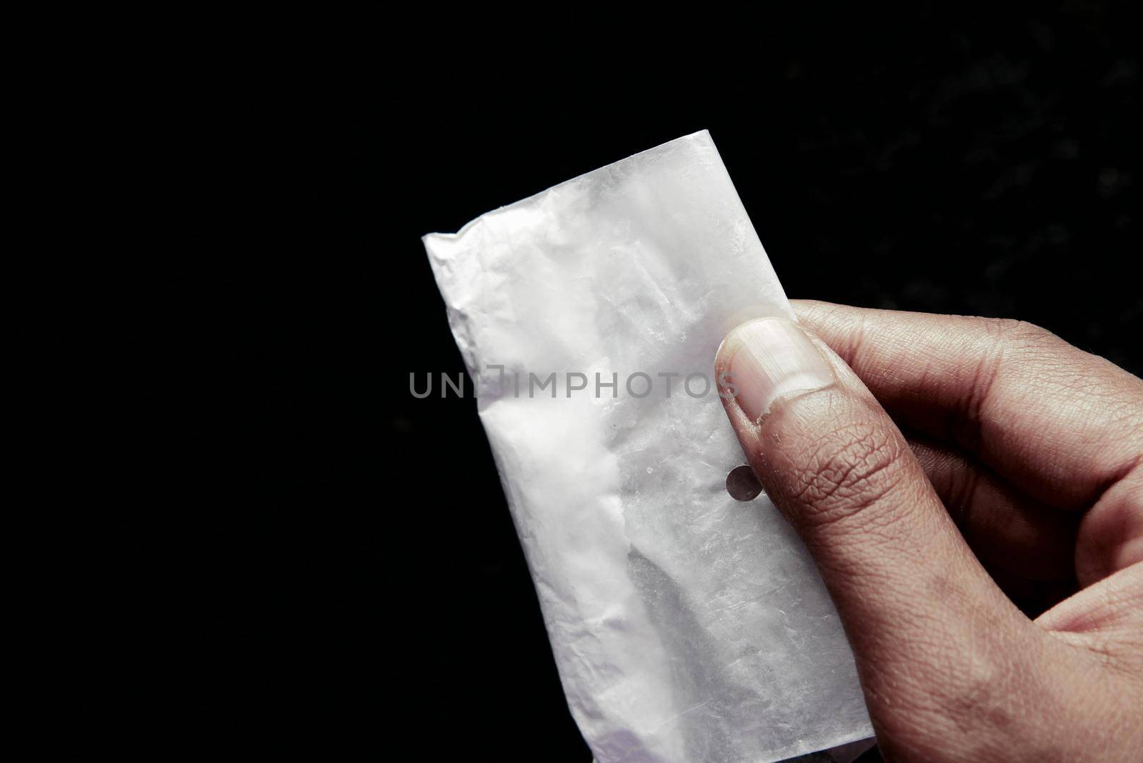 drug addiction concept with hand holding heroine packet on black backgrund.