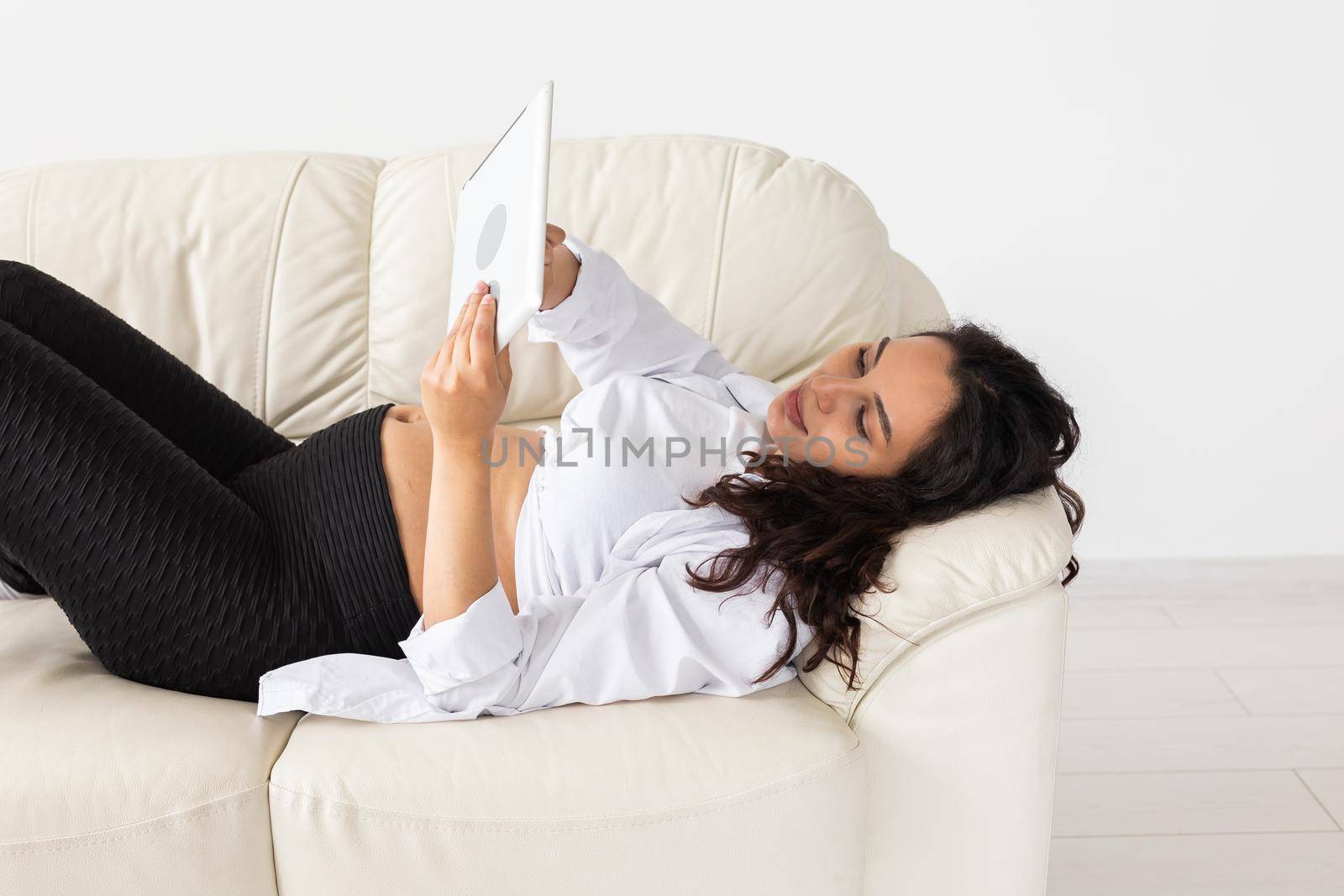 Latin pregnant woman using tablet computer sitting on sofa at home. Pregnancy and information for parenthood