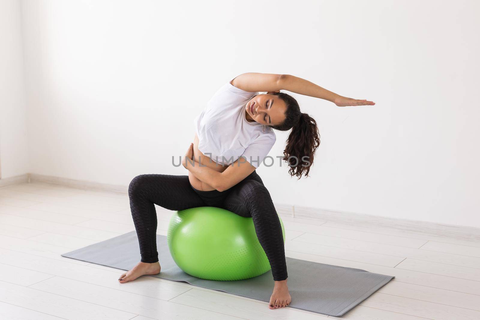 beautiful young pregnant woman doing exercise at home on fitball.