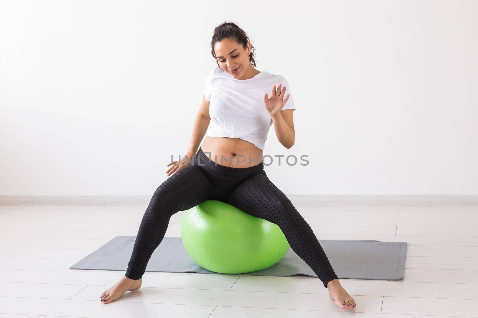 Cheerful pregnant woman dances while sitting on fitness ball. Well-being pregnancy, healthy lifestyle and positive concept