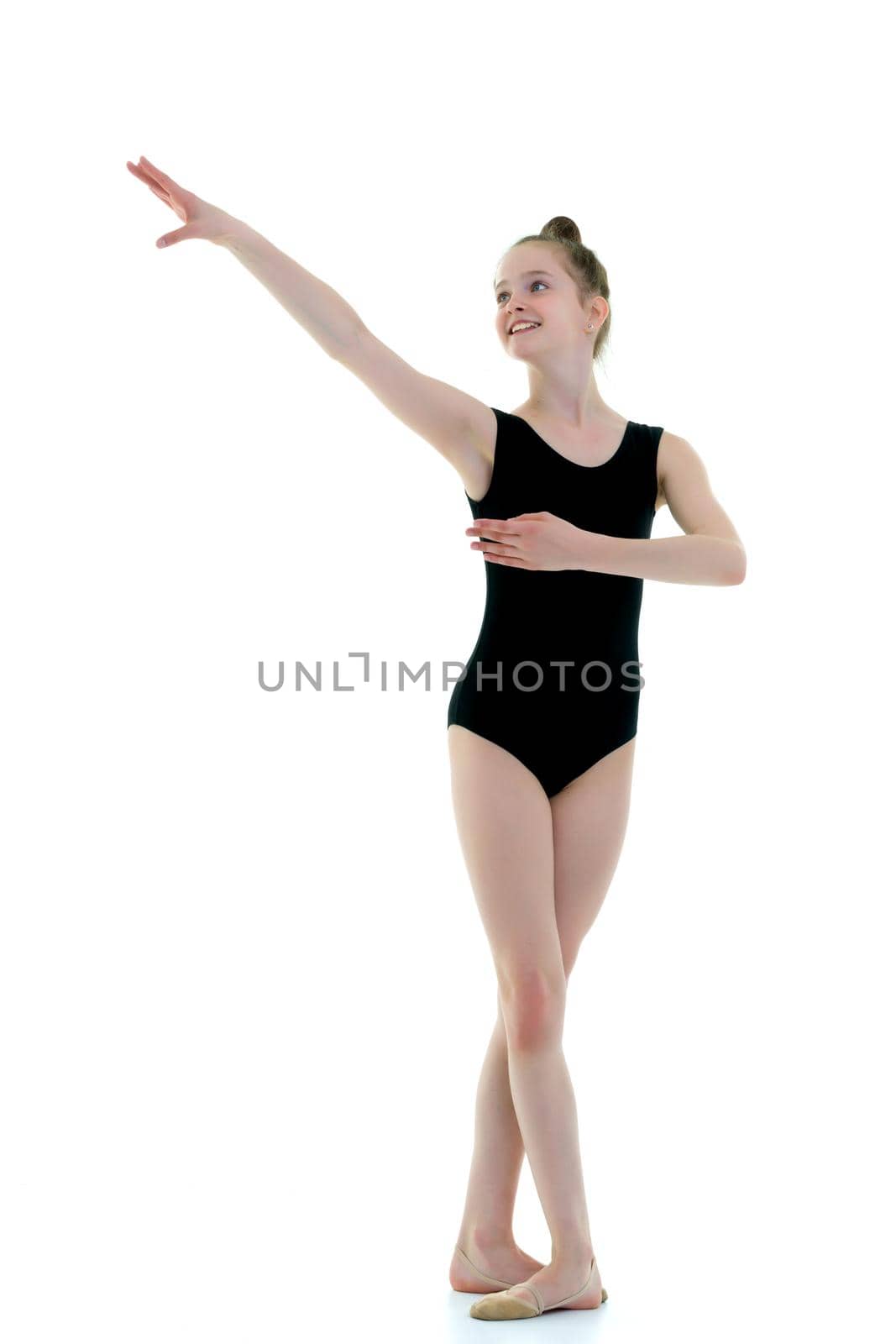 A nice little girl gymnast, in a beautiful gymnastic swimsuit for competitions. In full growth. The concept of advertising sports goods, the physical development of children. Isolated on white background.
