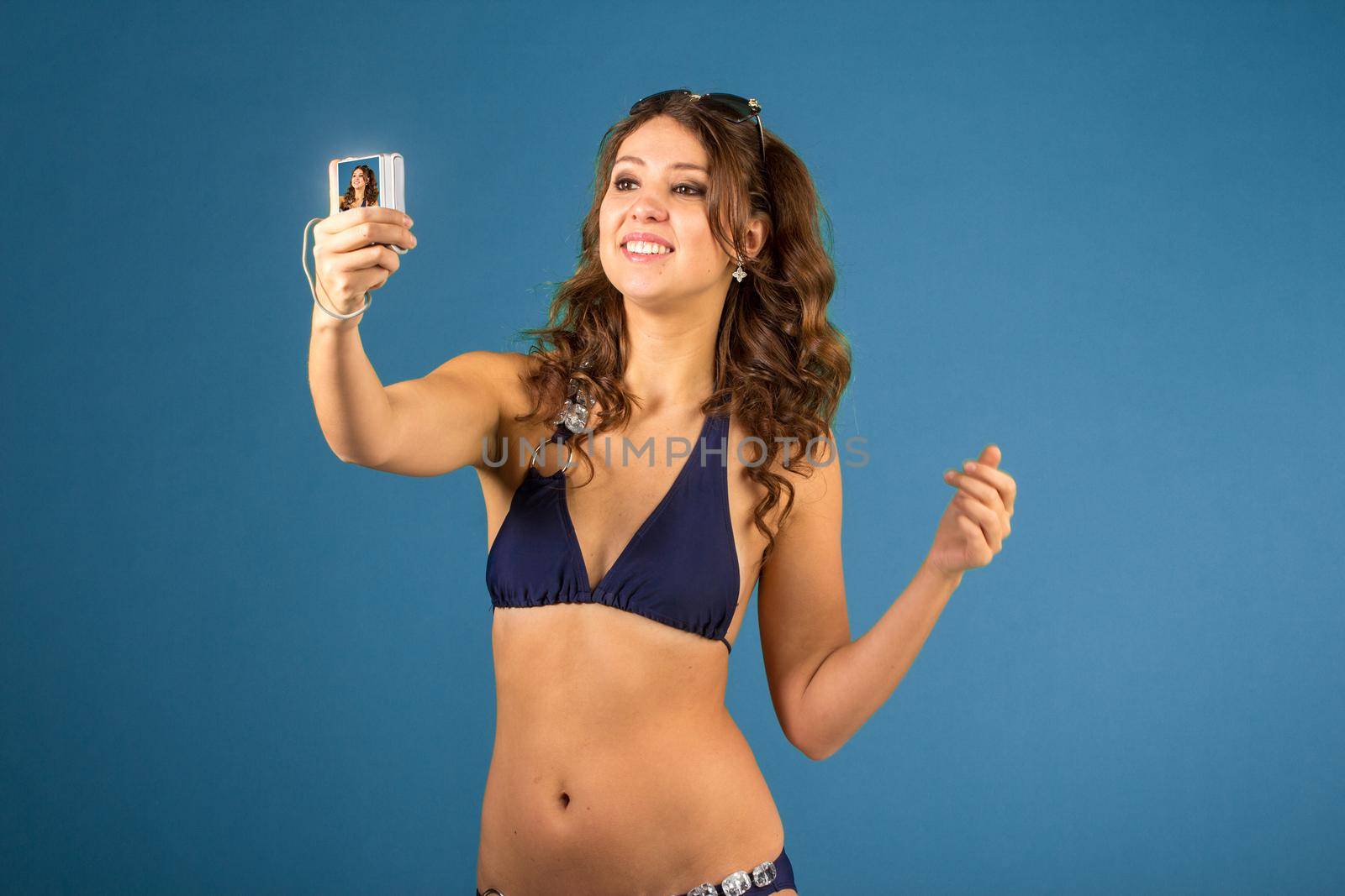 Portrait of smiling woman with camera and while standing against blue isolated background.