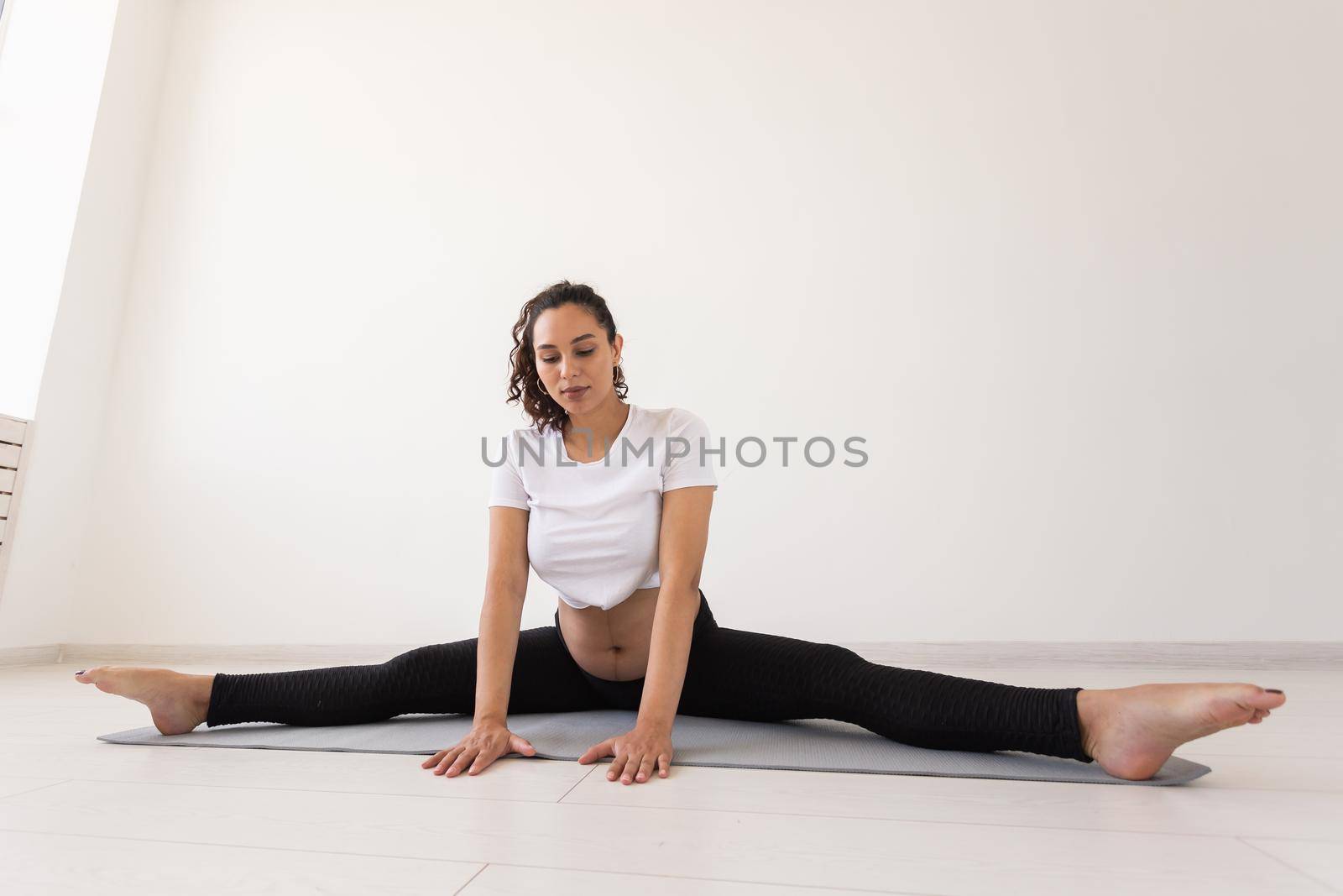 Purposeful pregnant woman exercises during yoga class and relaxes while sitting on a mat on the floor. Physical and mental preparation of the body for childbirth. Place for text