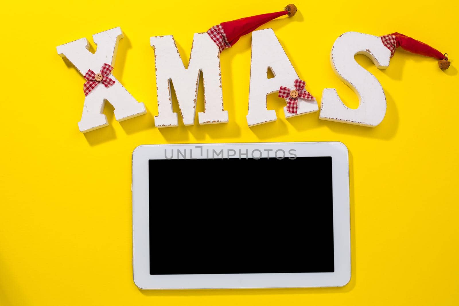 Smartphone with Christmas decorations. Christmas mock up template. View from above. yellow background