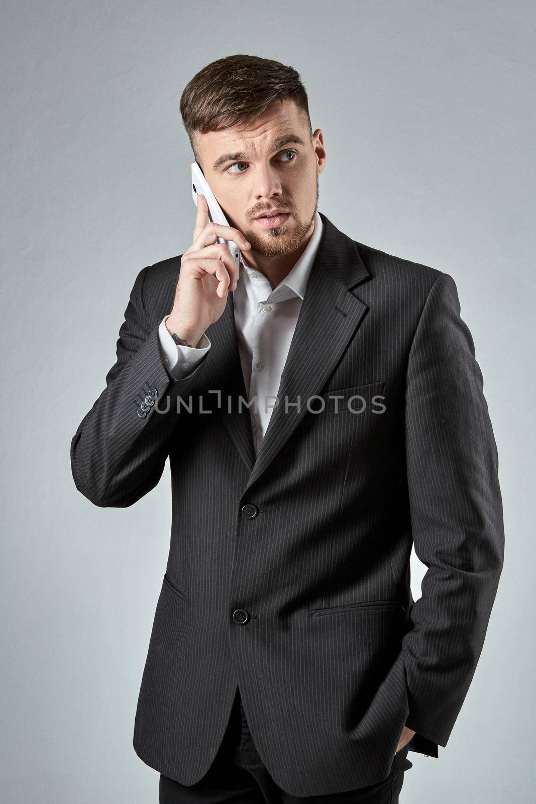 Portrait of a handsome businessman making a phone call against a grey background. Emotions