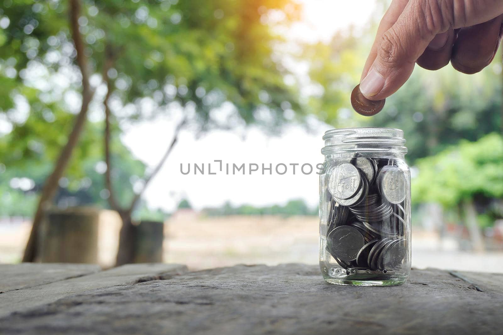 Money save tax income. businessman holding coins putting in glass on green nature background. Concept money save income