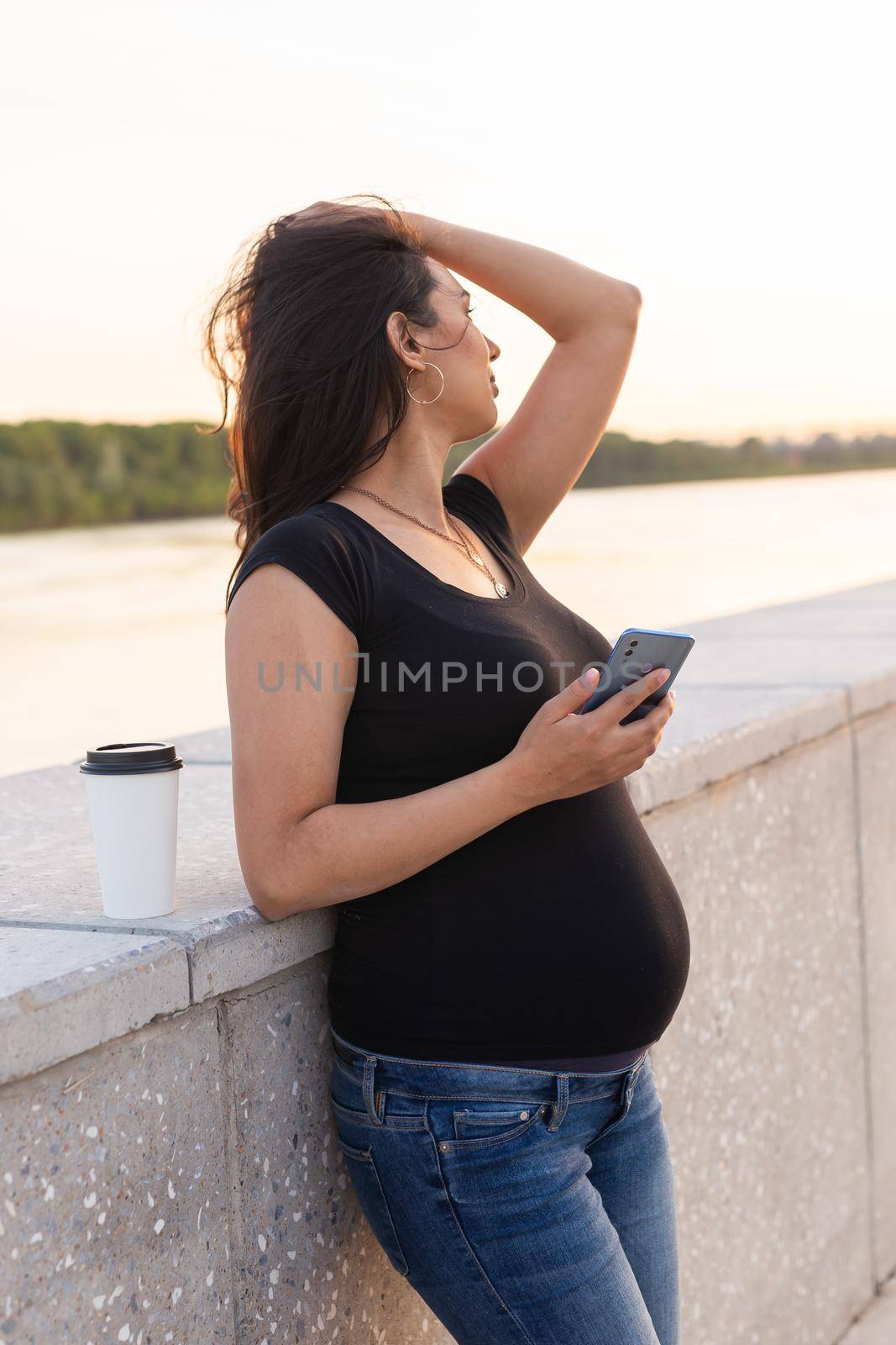 Pregnant woman feeling lovely and relax on embankment with warm light in morning