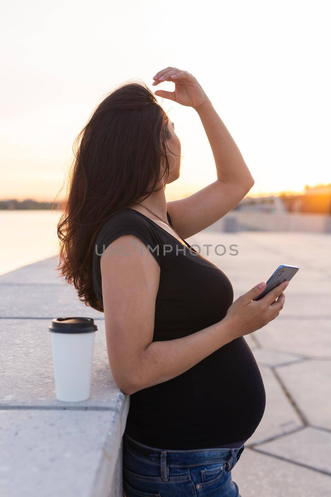 Pregnant woman feeling lovely and relax on embankment with warm light in morning