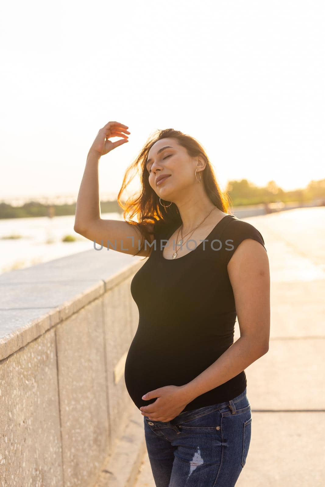 A Pregnant hispanic woman in the park, touching belly