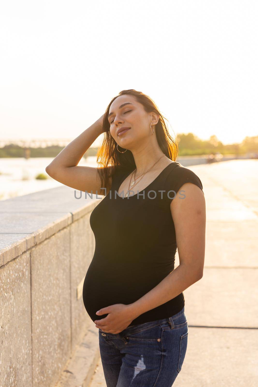 A Pregnant hispanic woman in the park, touching belly