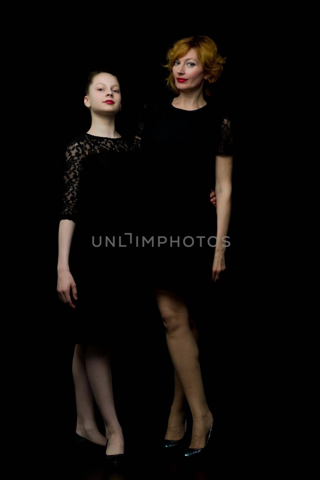 Happy family mom and little daughter, studio portrait.On black background